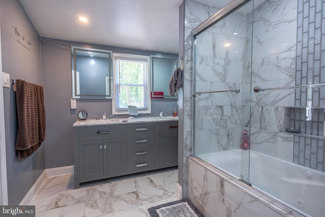 full bath with double vanity, marble finish floor, baseboards, tiled shower / bath, and a sink