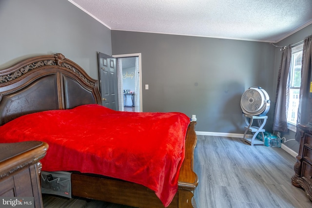 bedroom with ornamental molding, a textured ceiling, and wood finished floors