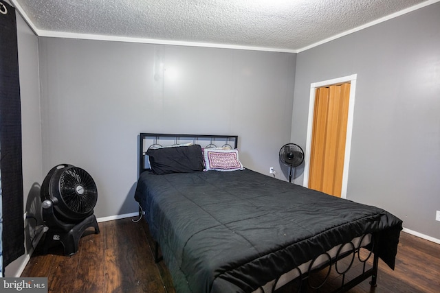 bedroom with baseboards, a textured ceiling, ornamental molding, and wood finished floors