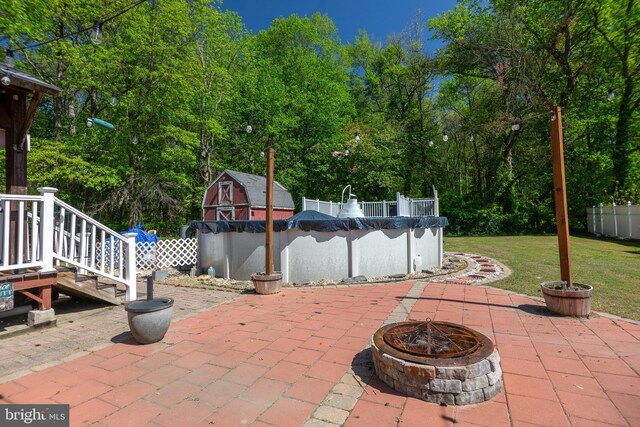 view of patio / terrace featuring fence, a covered pool, and an outdoor fire pit