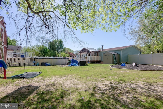 view of yard with fence, a storage shed, a deck, a fenced in pool, and an outdoor structure