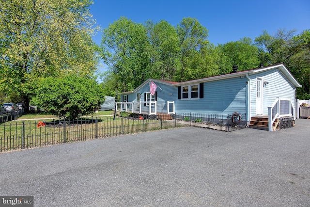 manufactured / mobile home with a deck, fence, and a front lawn