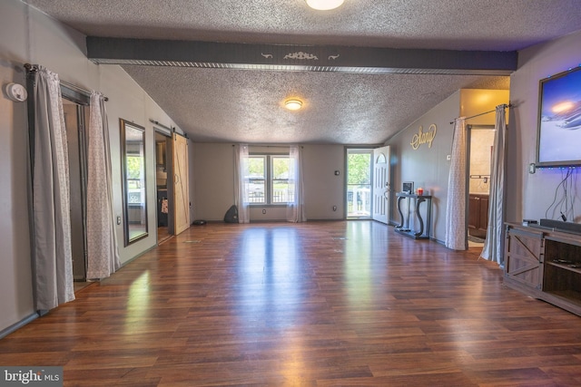 unfurnished living room featuring vaulted ceiling with beams, a textured ceiling, and wood finished floors
