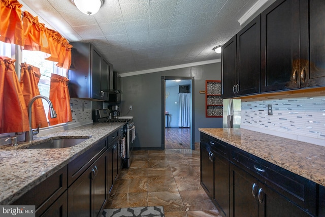 kitchen with backsplash, crown molding, gas stove, light stone counters, and a sink