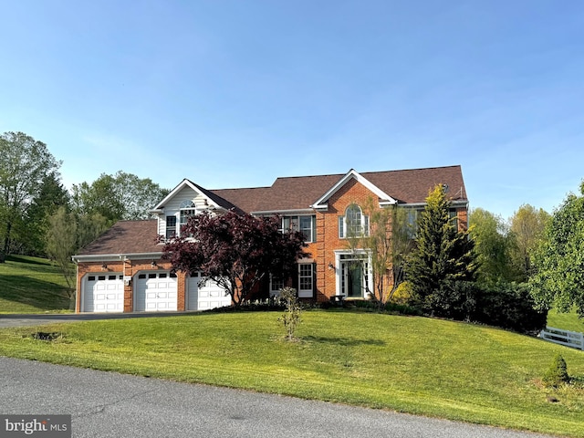 colonial home with brick siding, a front lawn, an attached garage, and driveway