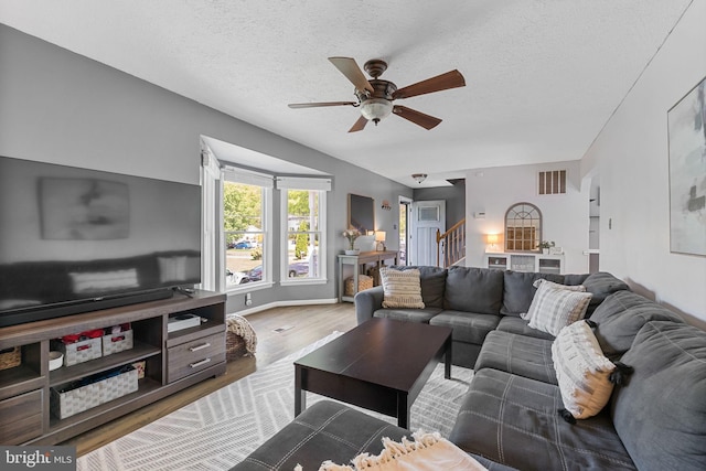 living room with visible vents, wood finished floors, stairway, a textured ceiling, and a ceiling fan