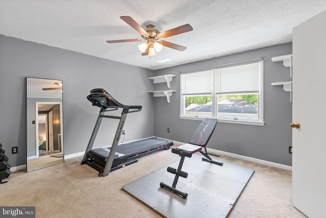exercise area featuring baseboards, carpet, a ceiling fan, and a textured ceiling