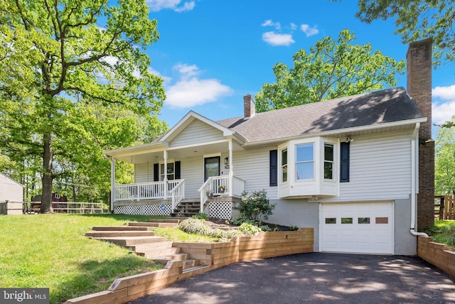 ranch-style home with aphalt driveway, a garage, a porch, a front yard, and a chimney
