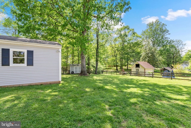 view of yard with a fenced backyard, a storage unit, and an outbuilding