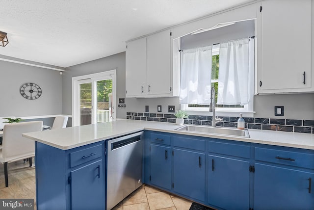 kitchen featuring a sink, light countertops, stainless steel dishwasher, and blue cabinets