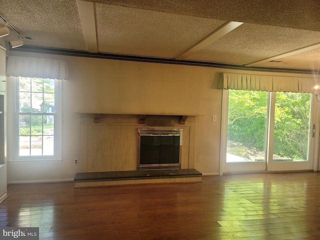 5895 Tibby Rd, Bensalem, PA 19020 - unfurnished living room featuring wood-type flooring, a tiled fireplace, a textured ceiling, and baseboards