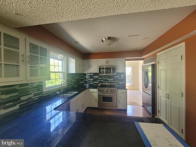 5895 Tibby Rd, Bensalem, PA 19020 - kitchen with stainless steel appliances, a sink, white cabinets, dark countertops, and backsplash