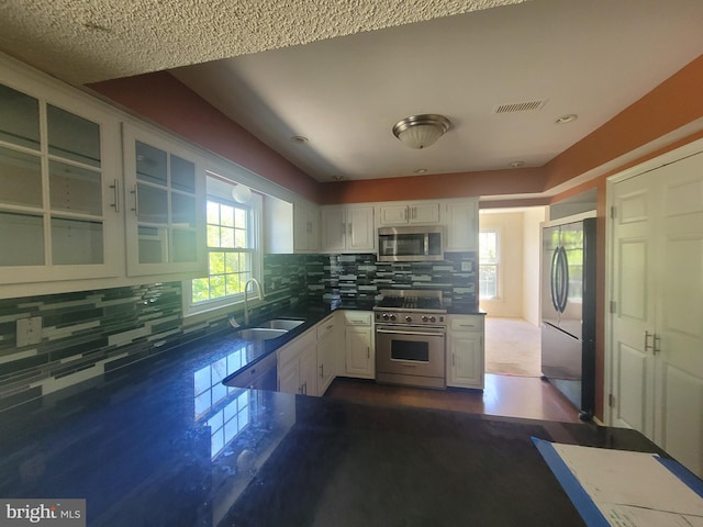 5895 Tibby Rd, Bensalem, PA 19020 - kitchen featuring stainless steel appliances, a sink, white cabinets, glass insert cabinets, and decorative backsplash