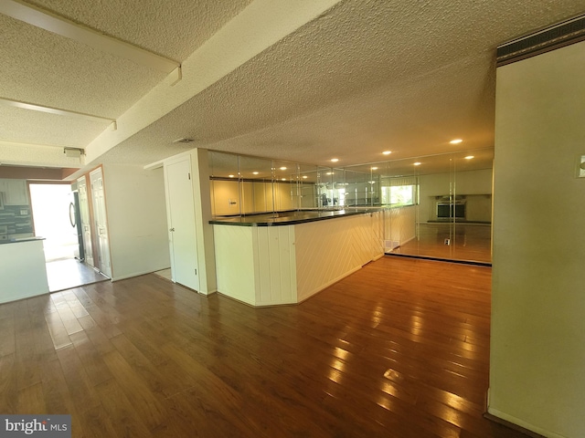 5895 Tibby Rd, Bensalem, PA 19020 - kitchen with hardwood / wood-style floors, a textured ceiling, dark countertops, a peninsula, and open floor plan