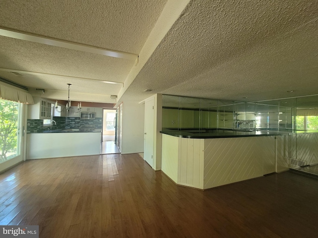5895 Tibby Rd, Bensalem, PA 19020 - kitchen with a textured ceiling, dark countertops, wood finished floors, glass insert cabinets, and stainless steel microwave