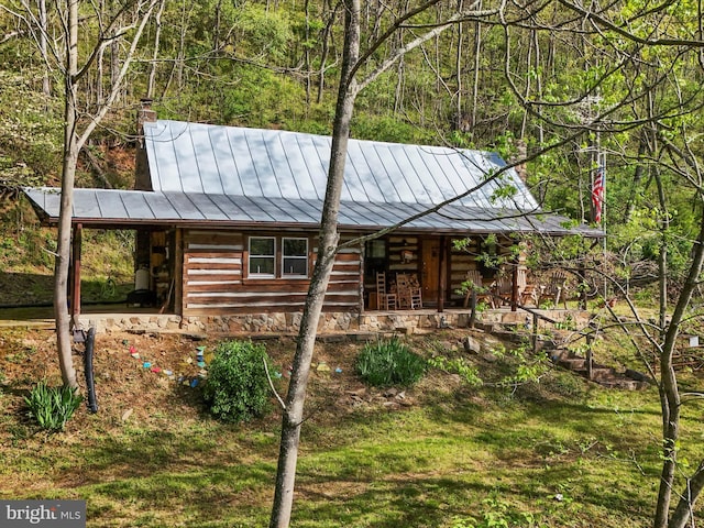 view of front of house featuring log exterior, a porch, a chimney, a standing seam roof, and metal roof