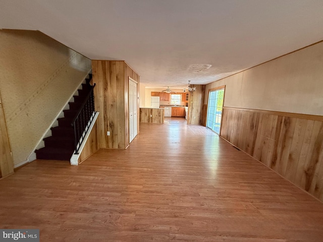2218 Trenton Ave, Bristol, PA 19007 - unfurnished living room featuring a chandelier, light wood finished floors, stairs, and wooden walls