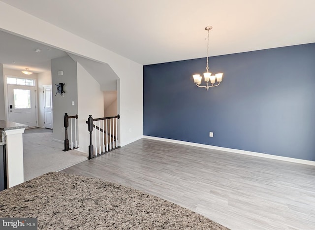 empty room featuring baseboards, wood finished floors, and a chandelier