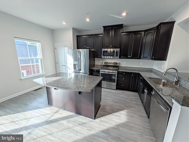 kitchen with a sink, appliances with stainless steel finishes, stone counters, and a kitchen island