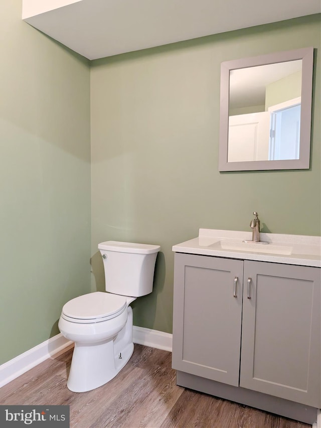 bathroom with baseboards, vanity, toilet, and wood finished floors