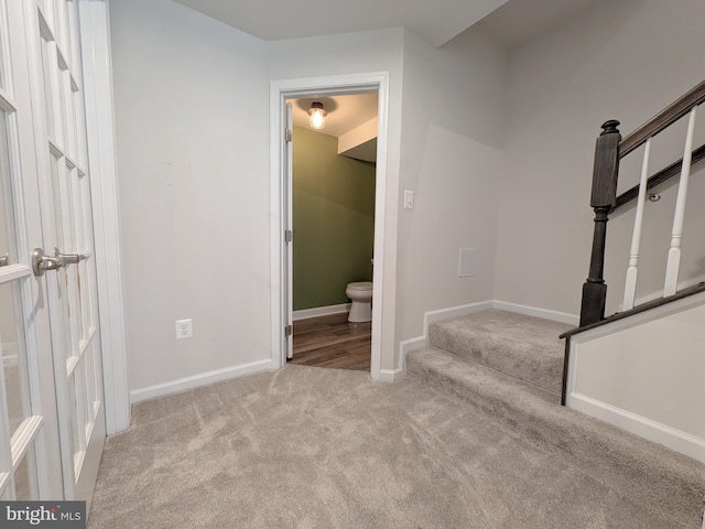 stairway featuring baseboards and carpet