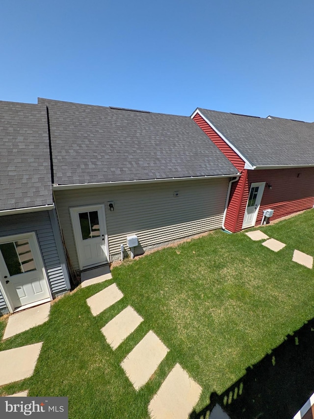 rear view of house with a shingled roof and a yard
