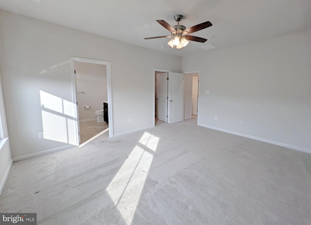 unfurnished bedroom with baseboards, a ceiling fan, ensuite bath, and light colored carpet