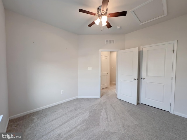 unfurnished bedroom with a ceiling fan, attic access, visible vents, carpet floors, and baseboards
