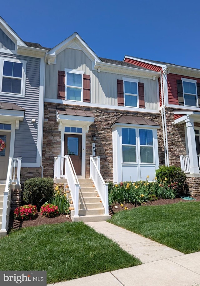 view of property with board and batten siding, a front yard, and stone siding
