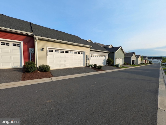 view of front of house with a garage, aphalt driveway, and a residential view