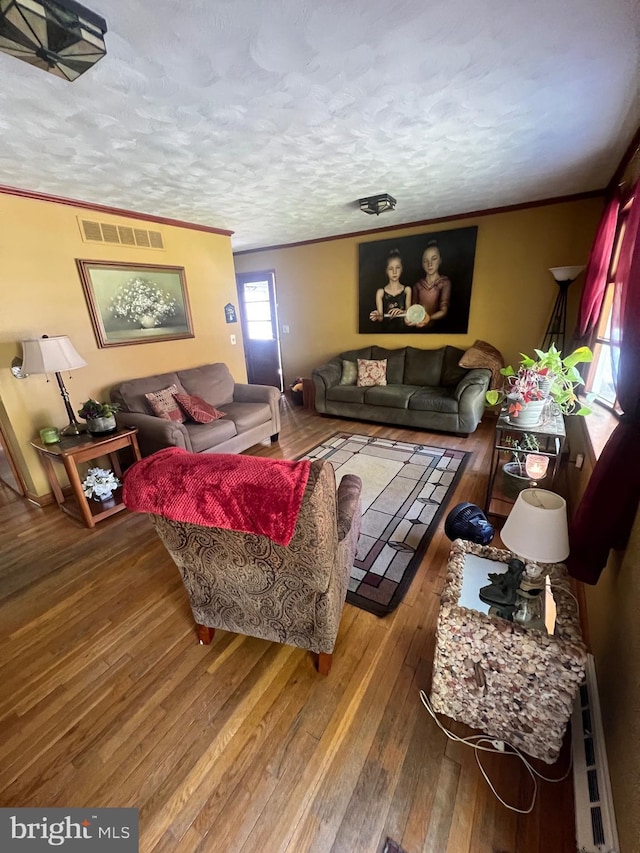 living room with ornamental molding, hardwood / wood-style flooring, a textured ceiling, and visible vents