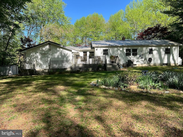 back of property featuring a lawn, a shed, an outbuilding, and a wooden deck