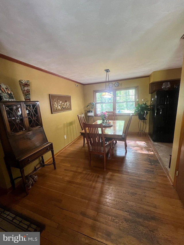 dining area with wood-type flooring, ornamental molding, and baseboards