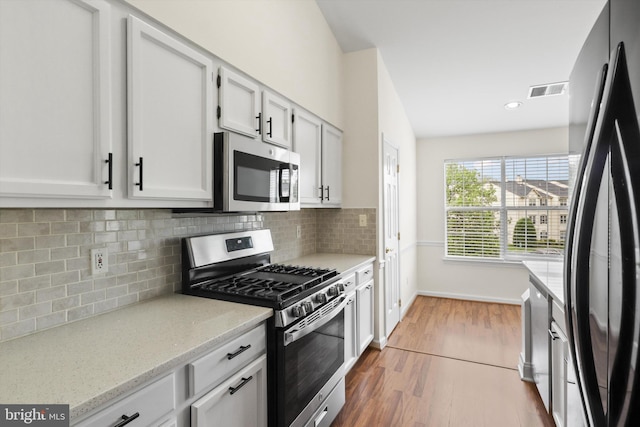 11014 Koman Cir Unit 304, Manassas, VA 20109 - kitchen featuring tasteful backsplash, wood finished floors, white cabinets, and appliances with stainless steel finishes