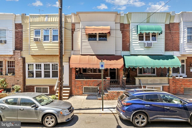 townhome / multi-family property with brick siding, entry steps, and cooling unit