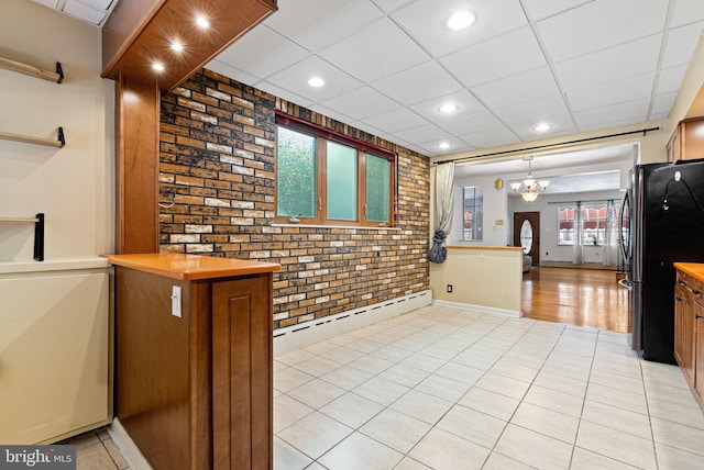 kitchen with freestanding refrigerator, recessed lighting, brick wall, and baseboard heating
