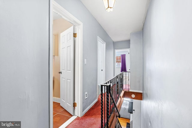 hall with baseboards, an upstairs landing, and tile patterned flooring