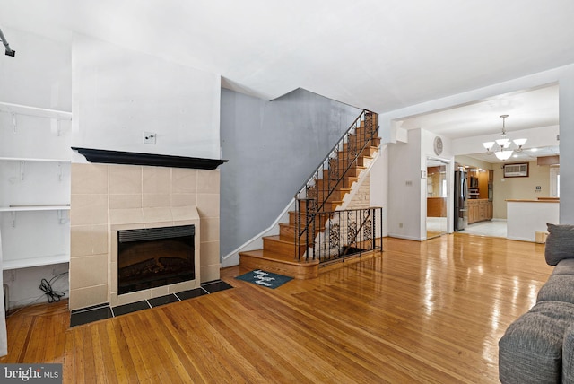 living area with stairs, wood finished floors, a notable chandelier, and a fireplace