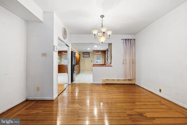 unfurnished dining area with light wood-type flooring, baseboards, a baseboard heating unit, a notable chandelier, and recessed lighting