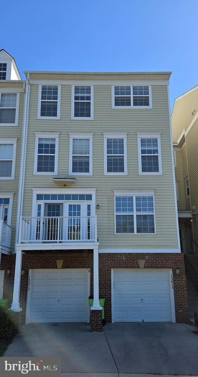 townhome / multi-family property featuring an attached garage, driveway, and brick siding