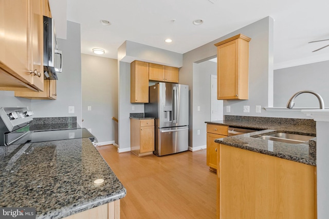 kitchen with electric range, a sink, dark stone countertops, light wood-type flooring, and stainless steel refrigerator with ice dispenser