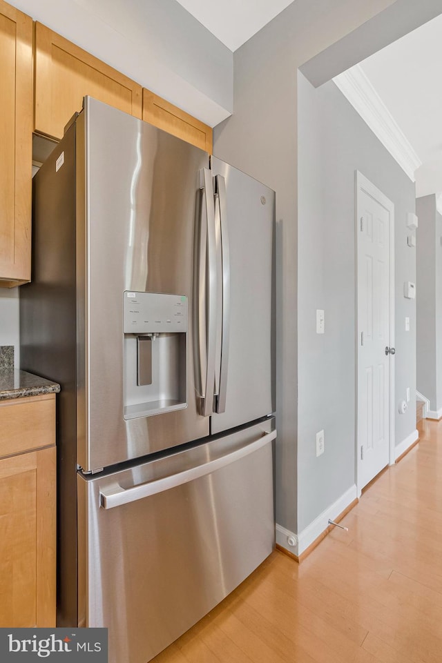 kitchen featuring crown molding, baseboards, stainless steel fridge, and light wood-style flooring