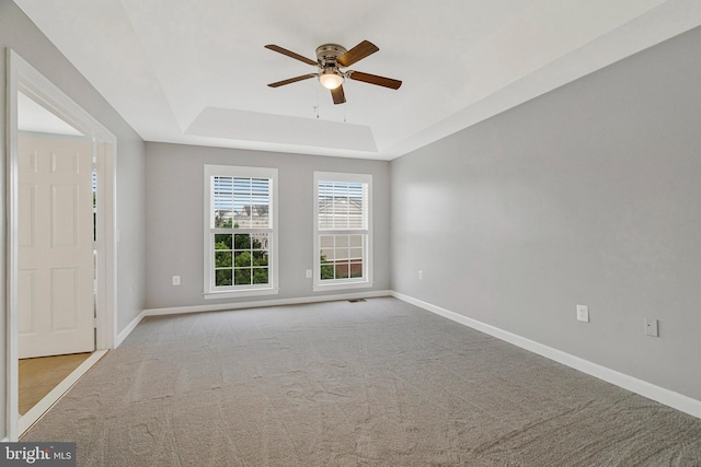 spare room featuring baseboards, a ceiling fan, a tray ceiling, and carpet flooring