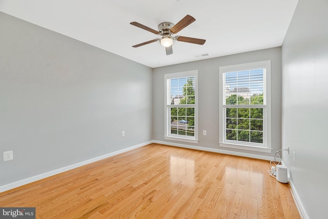 spare room with visible vents, a ceiling fan, baseboards, and wood finished floors