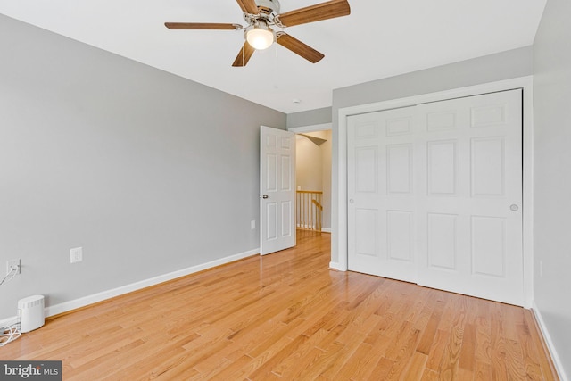 unfurnished bedroom featuring light wood-style floors, baseboards, ceiling fan, and a closet