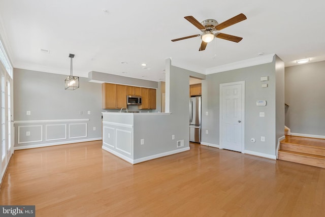 unfurnished living room featuring ornamental molding, light wood finished floors, a ceiling fan, and stairs