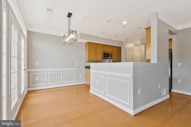 kitchen with visible vents, crown molding, stainless steel microwave, and light wood-type flooring