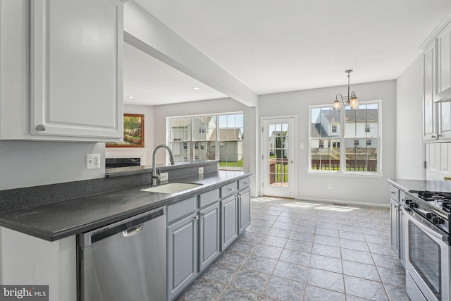 kitchen featuring dark countertops, white cabinetry, a chandelier, a sink, and appliances with stainless steel finishes