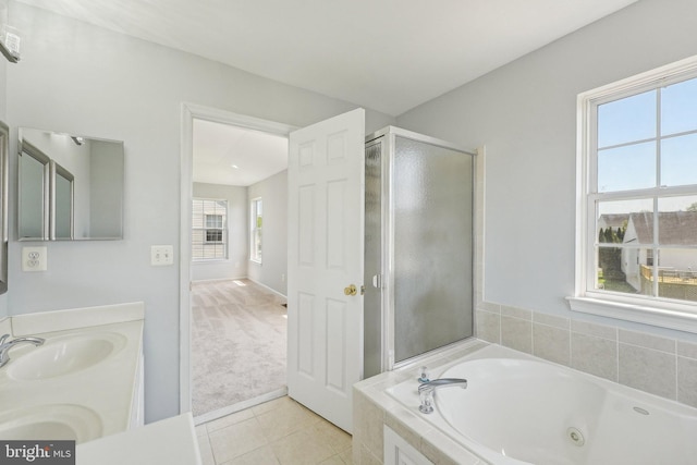 bathroom with a jetted tub, a sink, tile patterned flooring, and a wealth of natural light