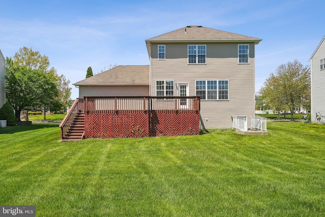 rear view of property featuring a lawn, a wooden deck, stairs, and roof with shingles